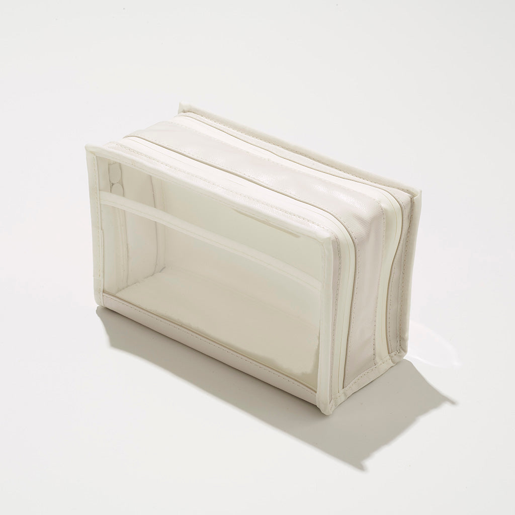 A white and clear rectangular cosmetic bag with creamy white faux leather trim, a transparent front panel, and a top zipper closure on a clean white background